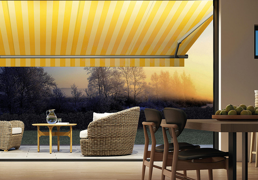 Malerische Terrasse bei tiefstehender Sonne mit gelb-weiß gestreifter Gelenkarm-Markise