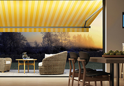 Malerische Terrasse bei tiefstehender Sonne mit gelb-weiß gestreifter Gelenkarm-Markise