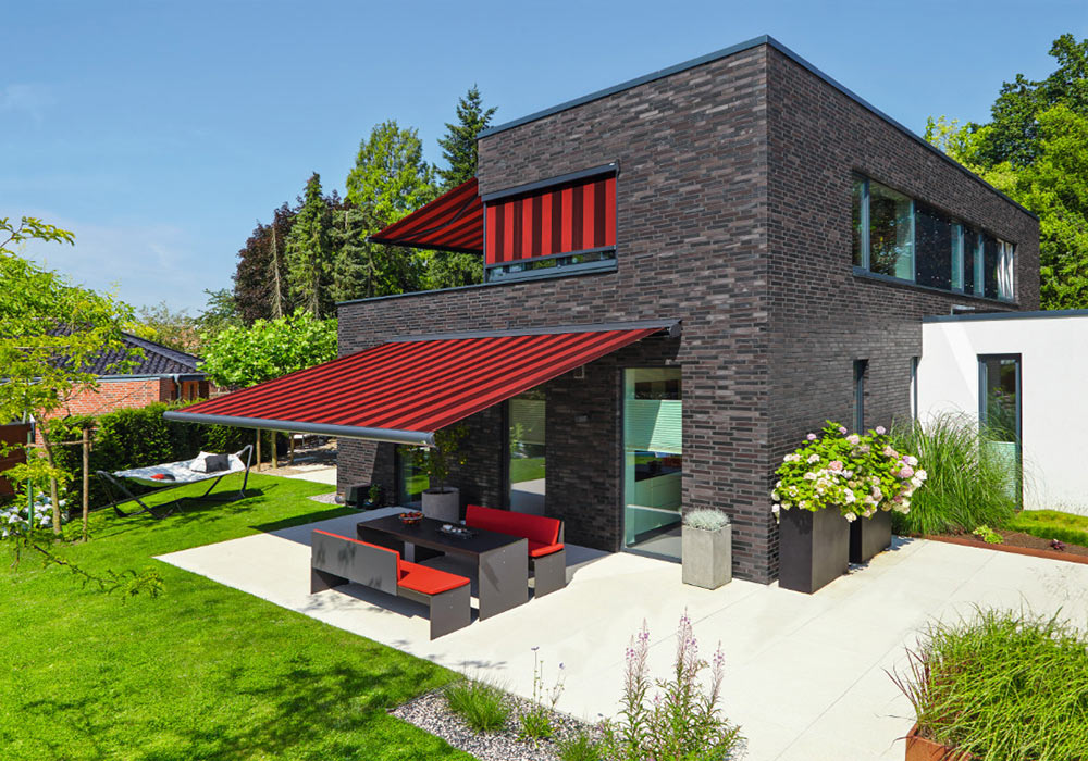 Schwarzes Klinkerhaus mit rot beschatteter Terrasse