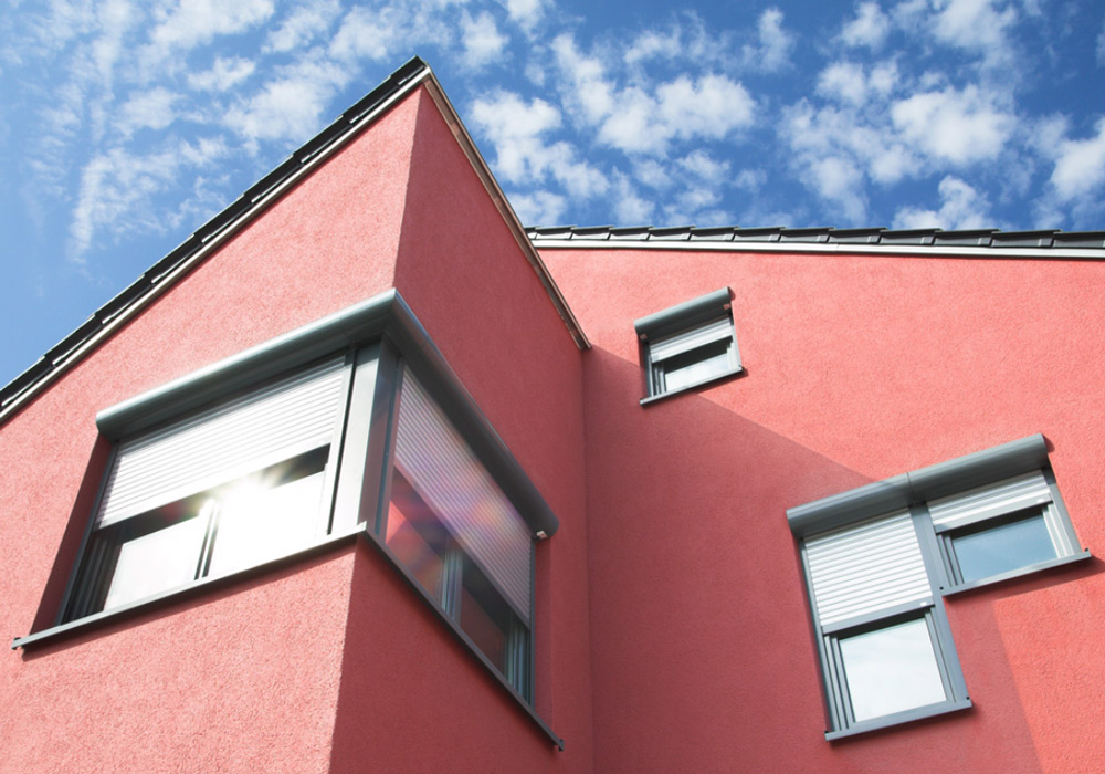 Rotes Haus mit vorgebauter Ecke mit grauen Fenstern